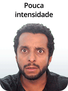 Composição com texto e fotografia. Na parte superior, está escrito “Pouca intensidade” em letras pretas. Abaixo, uma fotografia com foco no rosto de um homem de pele parda, cabelos cacheados, curtos e pretos, e barba preta, com o rosto voltado para frente. Ele olha para a frente com os olhos bem abertos, sobrancelhas erguidas e levemente contraídas, e a boca entreaberta